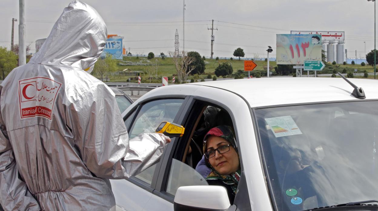 Miembros de la Media Luna Roja Iraní examinan a personas con posibles síntomas del coronavirus, mientras la policía bloqueaba la carretera de Teherán a Alborz