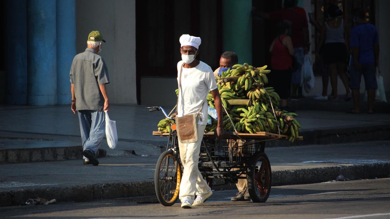 Un vendedor, con mascarilla, tira de su carro en La Habana