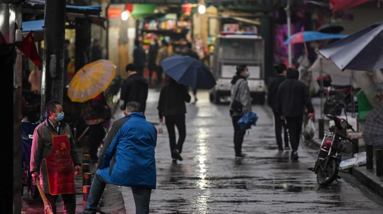 Las personas usan mascarillas y guardan la distancia social como medidas preventivas contra la propagación del Covid-19, en una calle de Wuhan