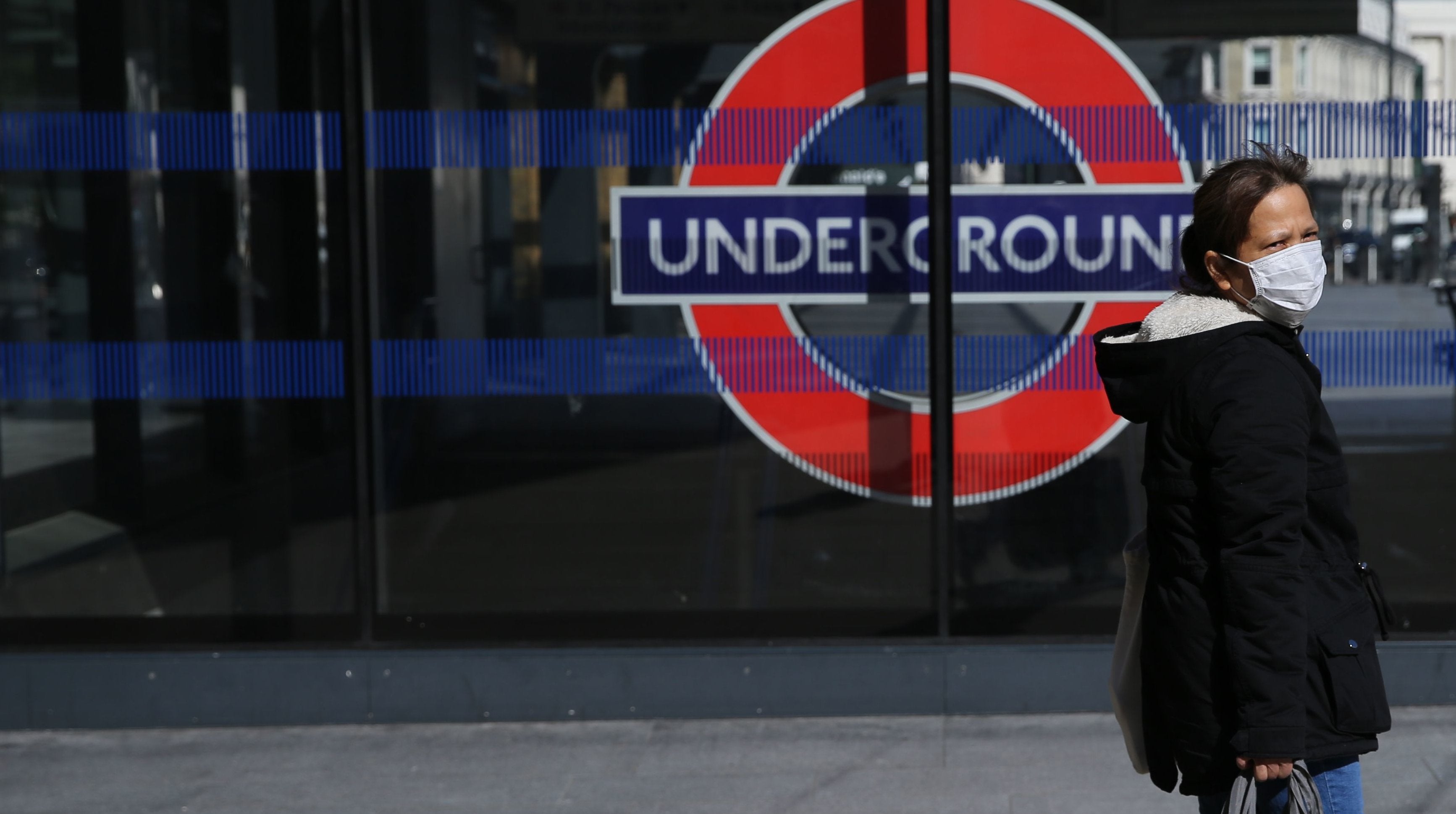 Coronanirus: Una mujer con mascarilla junto a una estación en Londres