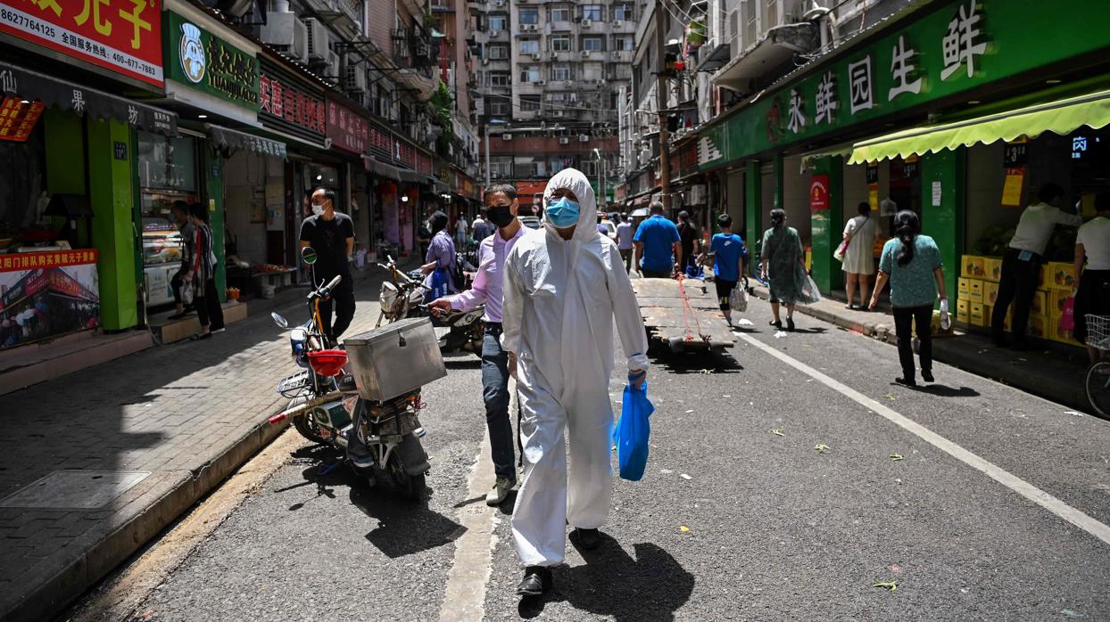 Un hombre camina por las calles de Wuhan con mascarilla y equipamento contra el virus