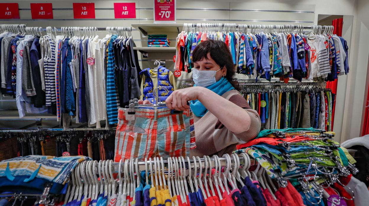 Una mujer prepara una tienda de ropa de niño para su próxima reapertura