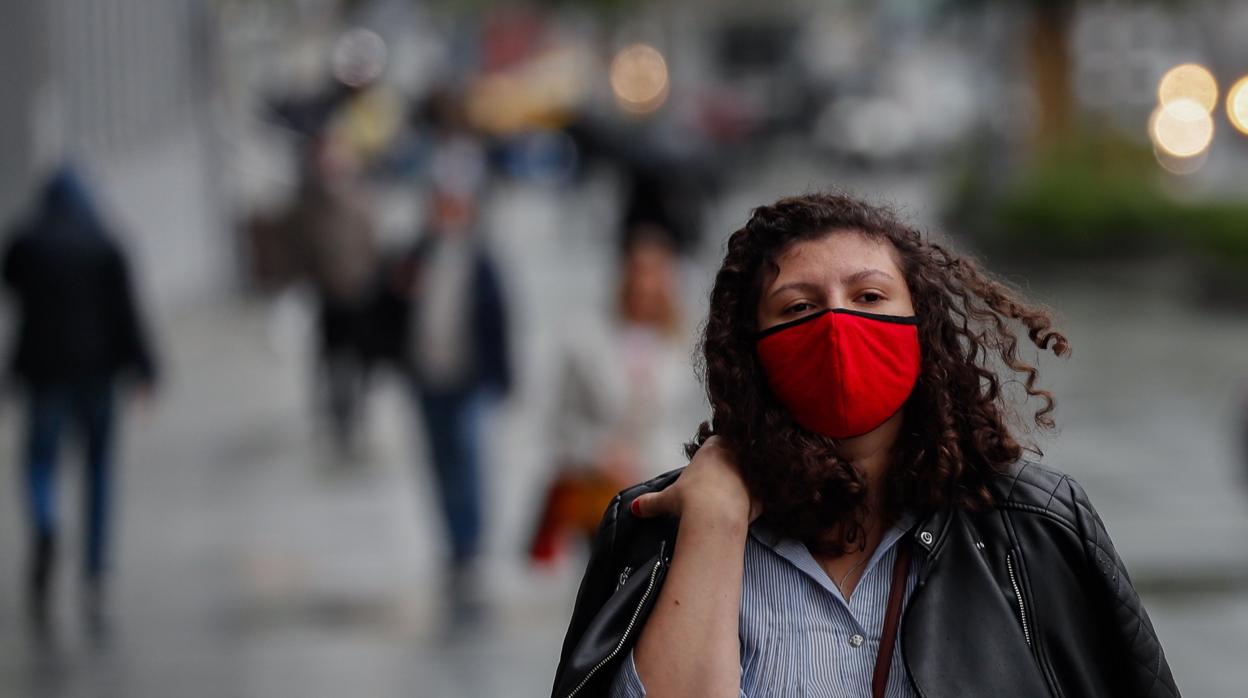 Una mujer rusa pasea protegida con su mascarilla por una calle de Moscú