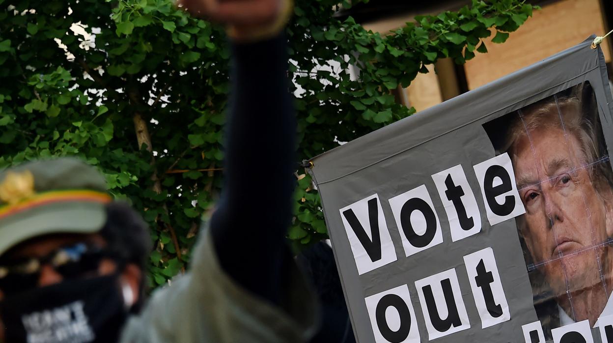 Un manifestante levanta el puño frente a un cartel que llama a votar a Donald Trump durante una protesta pacífica contra el racismo