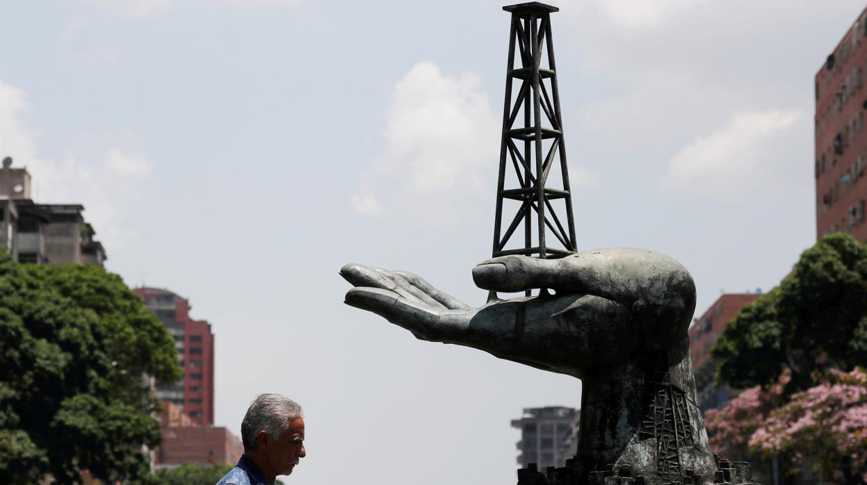 Un hombre pasa frente a una escultura de la compañía estatal Pdvsa