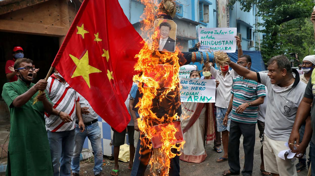 Un grupo de ciudadanos indios queman una bandera china y un retrato de Xi Jinping