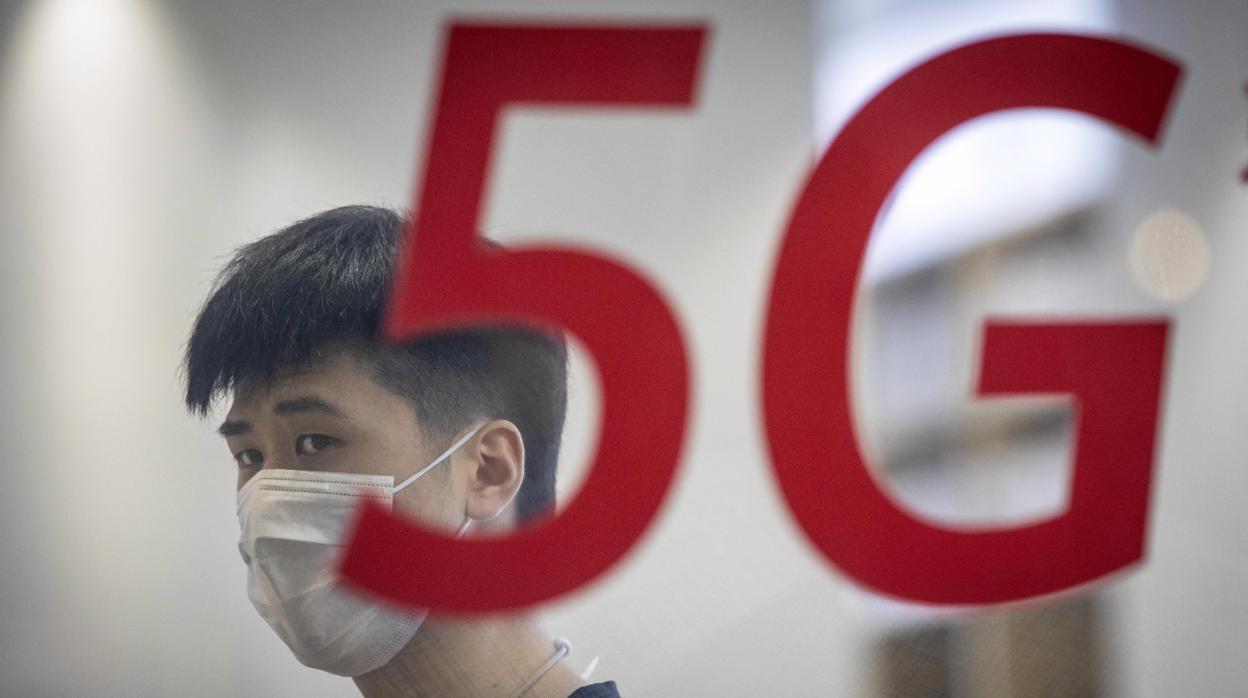 Un hombre con mascarilla, a través de la ventana de un establecimiento de Huawei en Shanghái