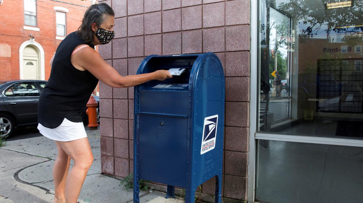 Una mujer desposita sus cartas en un buzón de Filadelfia