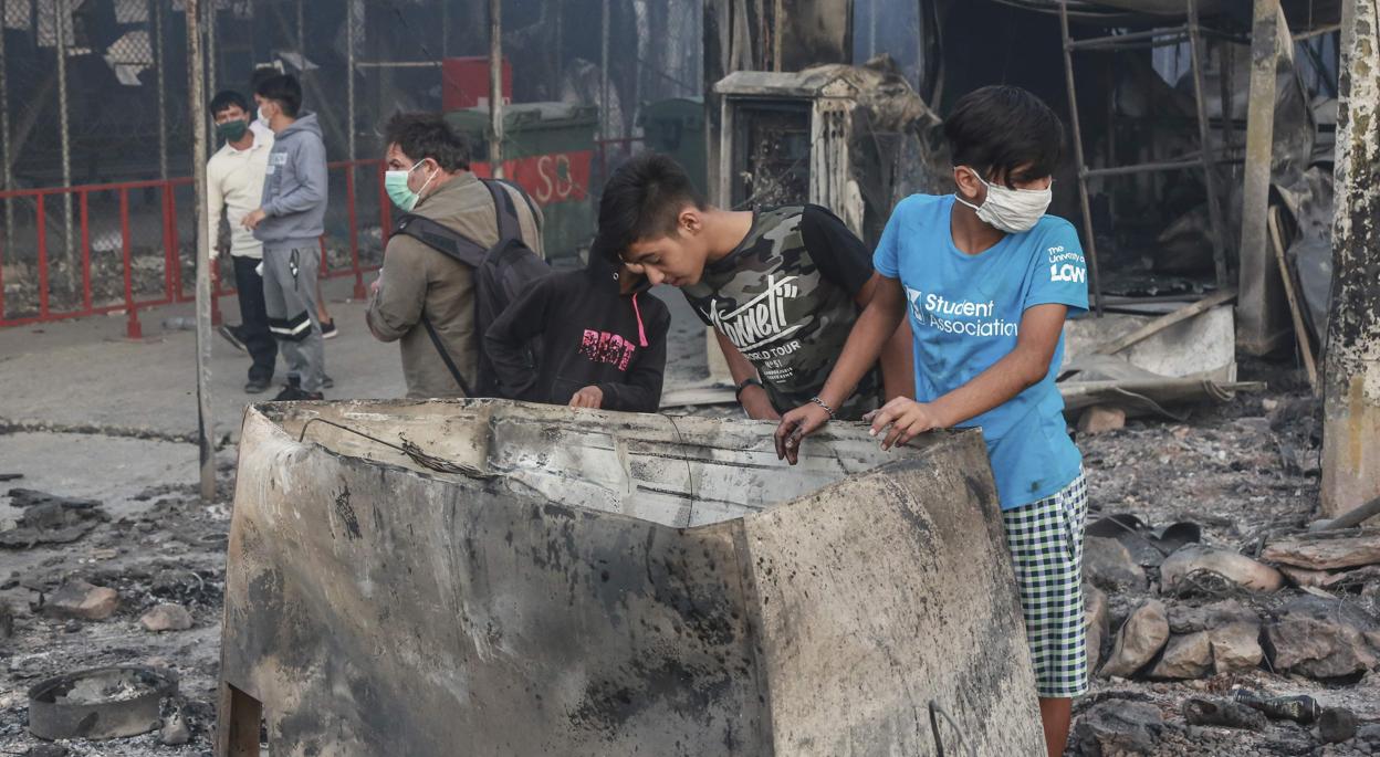 Los niños miran escombros en el campamento quemado de Moria en la isla de Lesbos después de que estalló un gran incendio