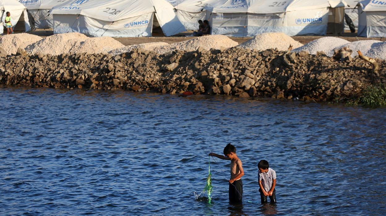 Dos niños juegan en el mar junto al nuevo campo de refugiados de Lesbos