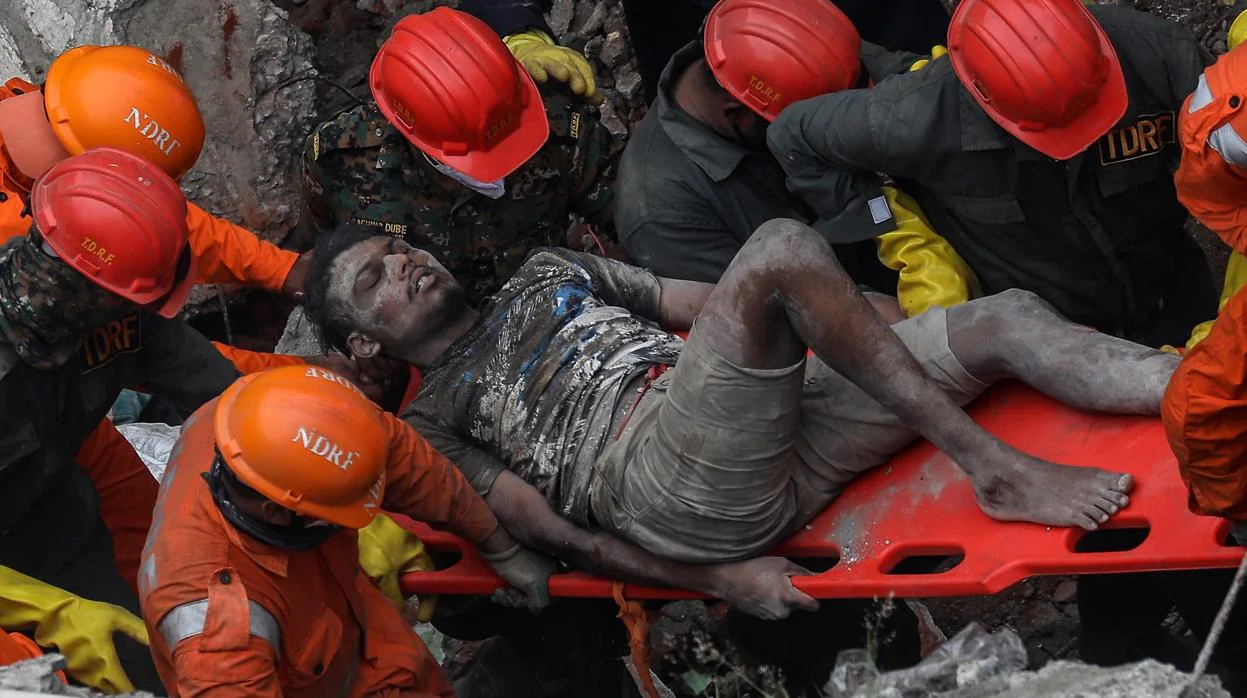 La Fuerza Nacional de Manejo de Desastres (NDRF por sus siglas en inglés) rescatan de los escombros, a un superviviente del edificio residencial