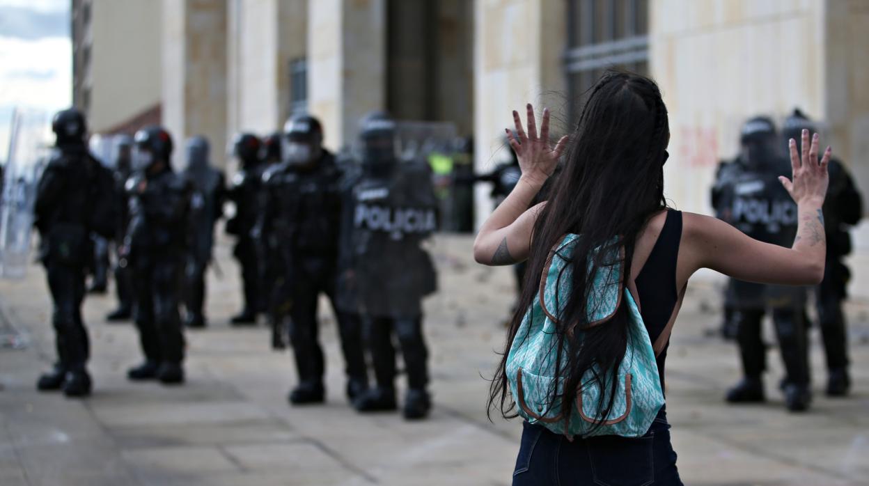 Una mujer levanta las manos mientras se enfrenta a la policía antidisturbios durante una protesta