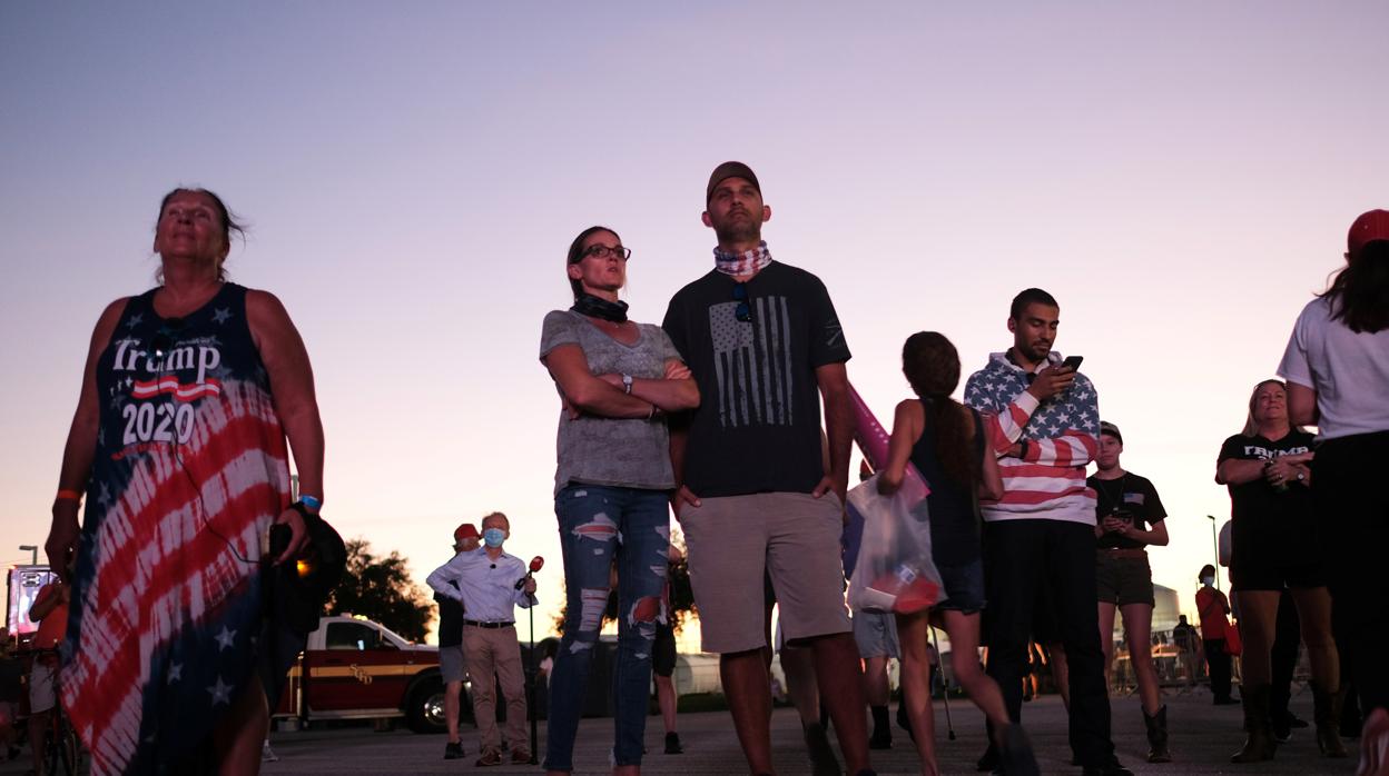 Un grupo de seguidores de Trump siguen su mitin por pantalla de TV en Orlando