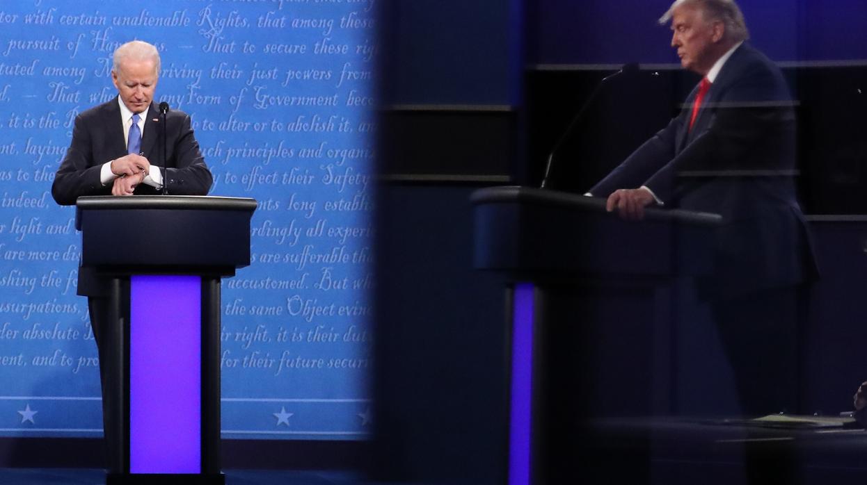 Joe Biden consulta su reloj durante el debate con Trump, reflejado a la derecha