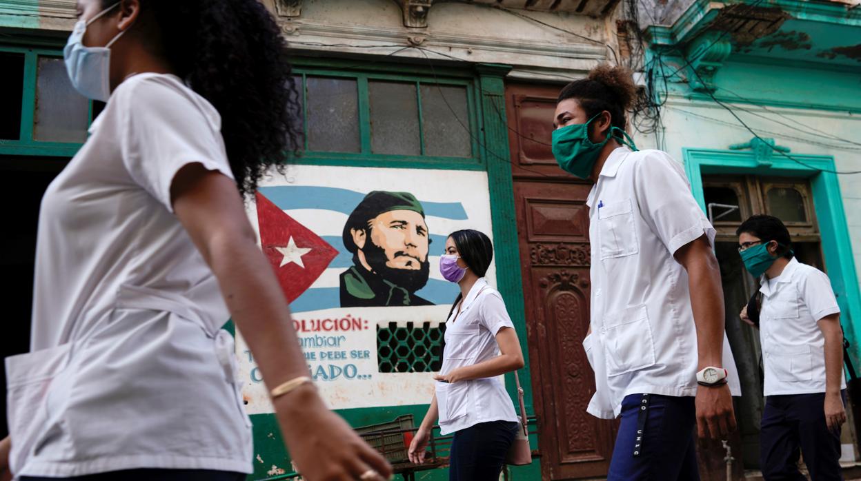 Estudiantes de Medicina pasan frente a una imagen de Fidel Castro en La Habana