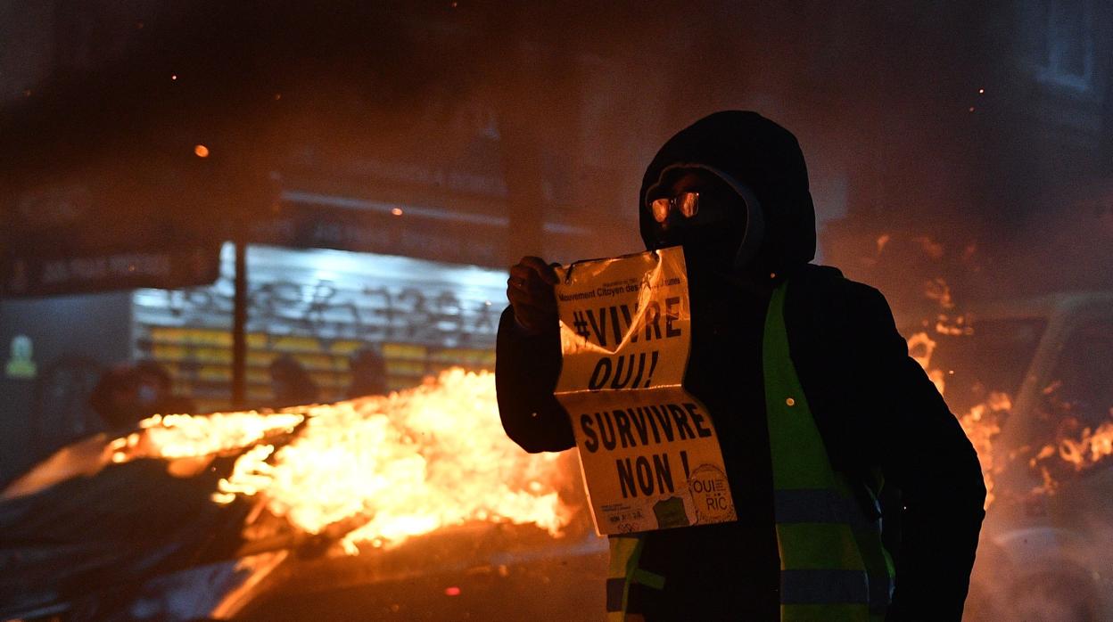 Un manifestante exhibe en París un cartel que con el mensaje «¡Vivir sí! ¡Sobrevivir no!»