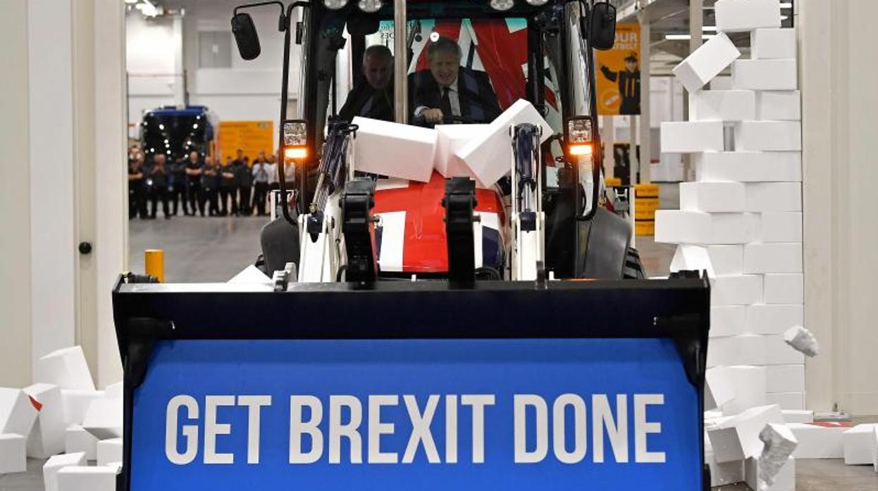 Boris Johnson derriba un muro postizo con una máquina elevadora que lleva un lema a favor del Brexit, durante un acto de campaña en diciember de 2019