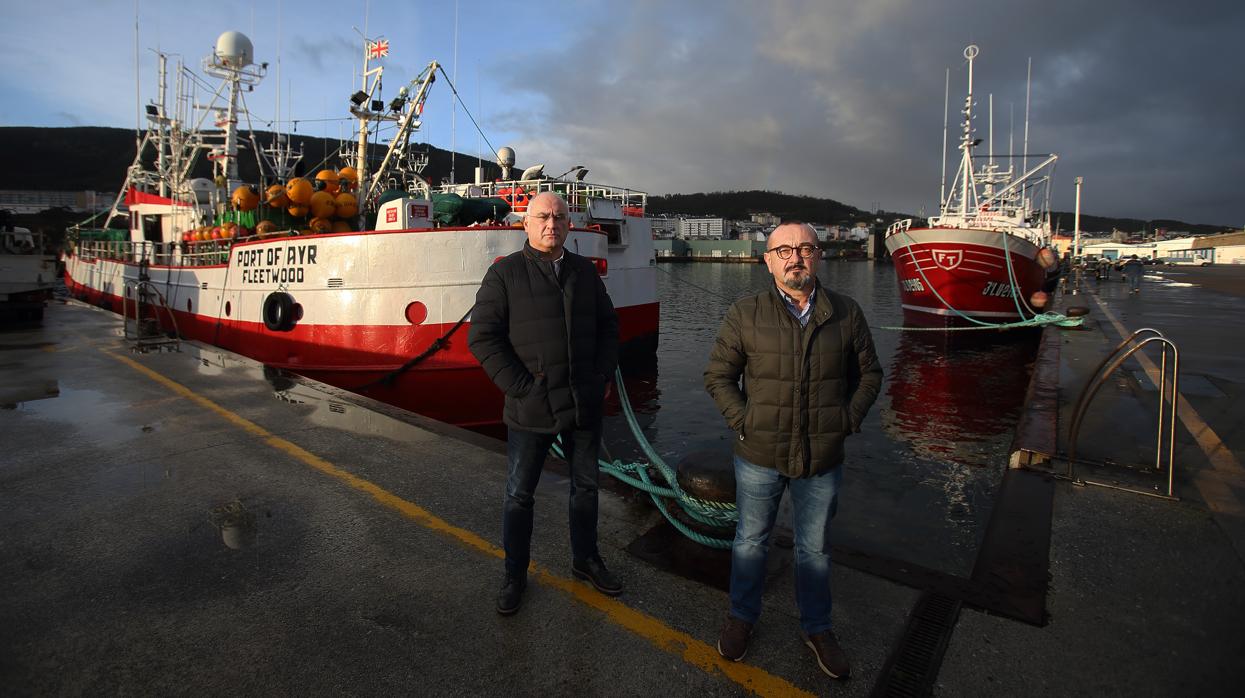 Raul Canoura y Sergio López, en el puerto de Burela junto a un barco de bandera británica