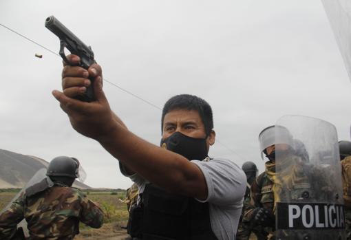 Un miembro de la Policía apunta su arma a los manifestantes