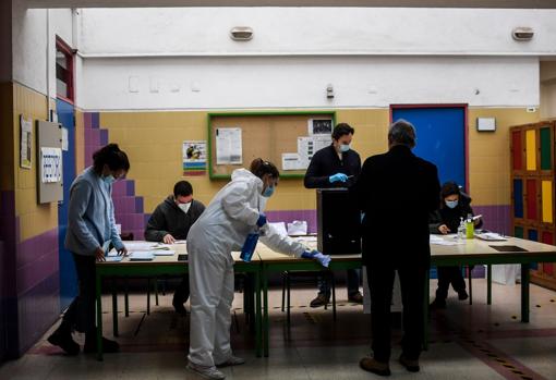 Una mujer, con traje protector, se ocupa de desinfectar un colegio electoral en Lisboa