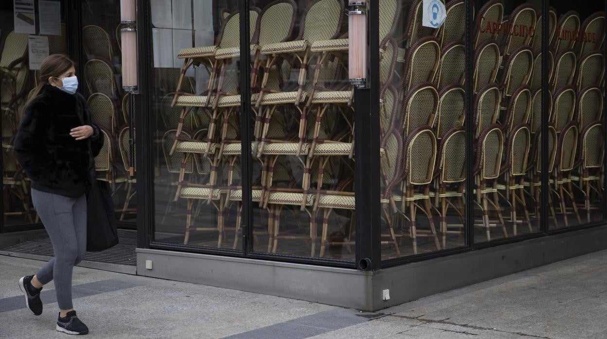 Una mujer camina junto a un restaurante cerrado en París