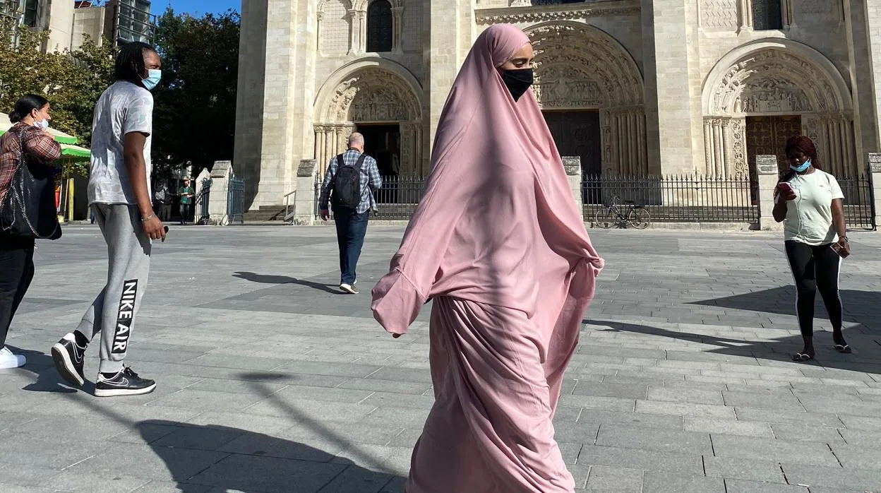 Una mujer camina delante de la catedran de Saint Denis