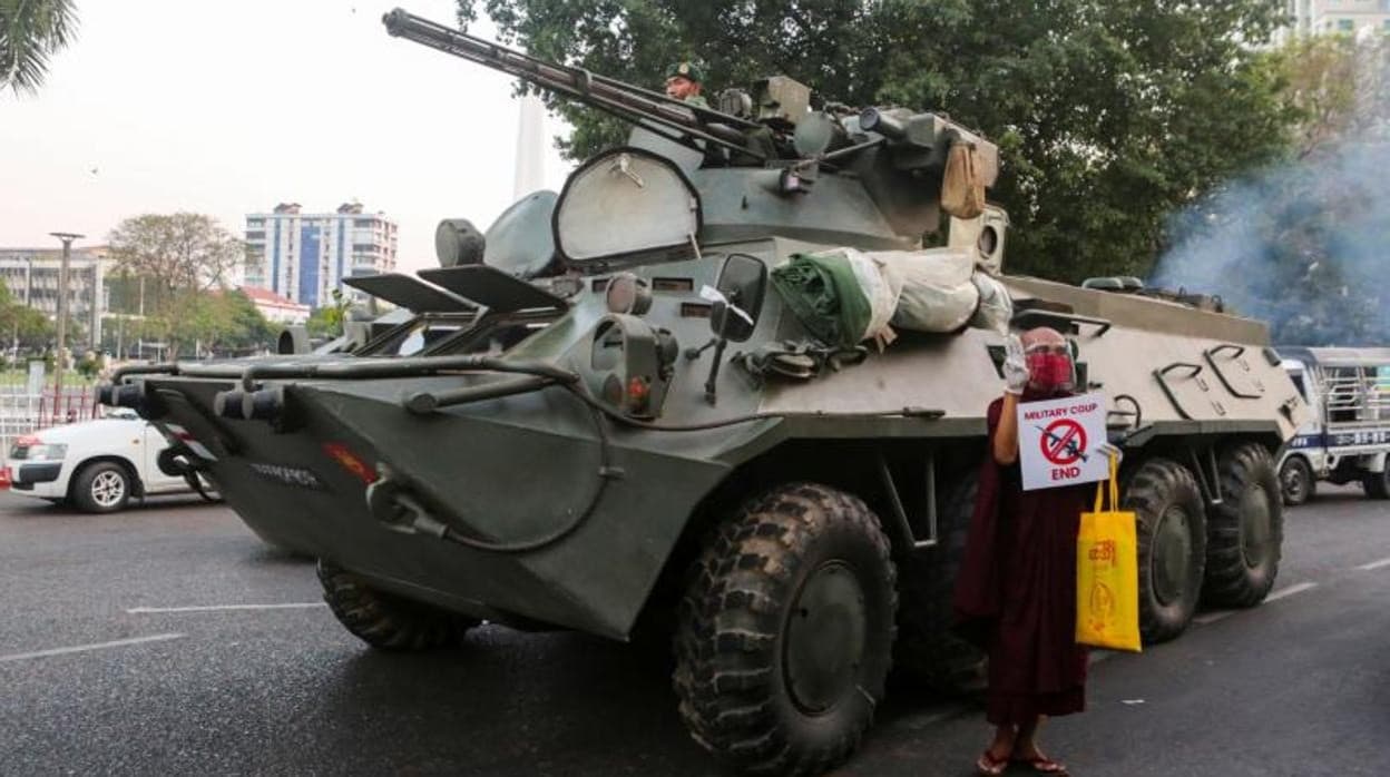 Un monje budista muestra un cartel contra el golpe militar ante un vehículo blindado en Rangún
