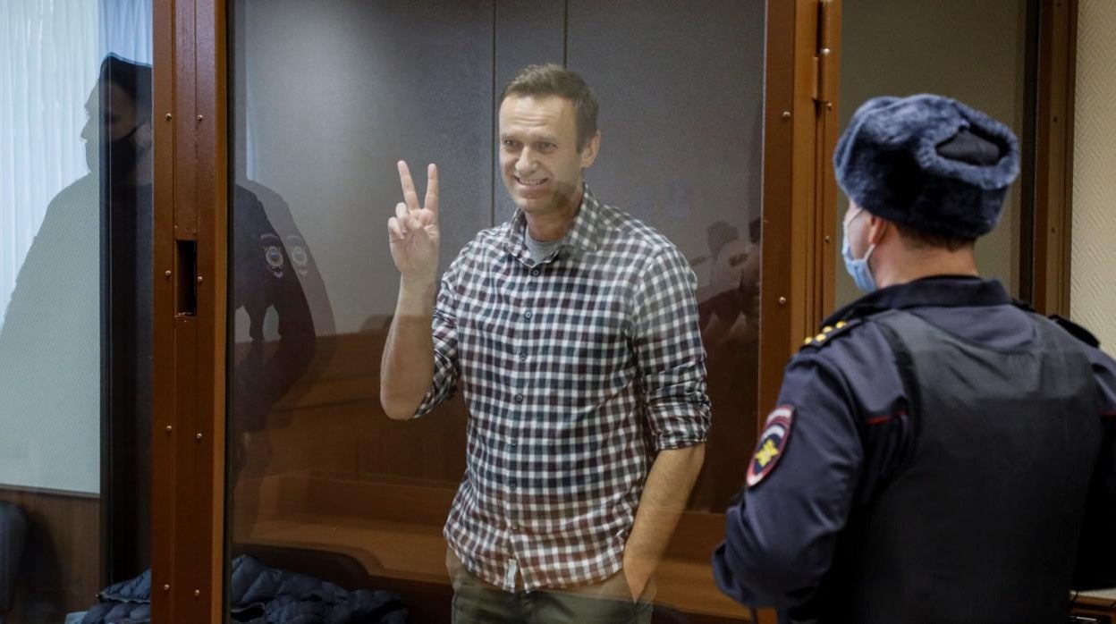 El líder opositor ruso hace el signo de la victoria desde una celda de cristal durante una nueva sesión de su batalla en los tribunales