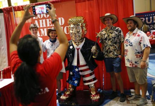 Asistentes a la Conferencia conservadora en Orlando (Florida) se fotografían con la estatua dorada de Donald Trump