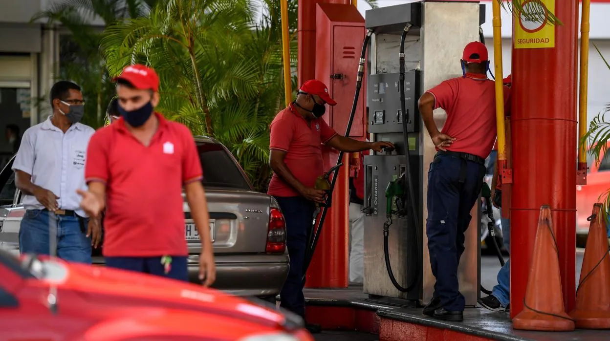 Un trabajador de una estación de servicio respota combustible a un coche en Caracas
