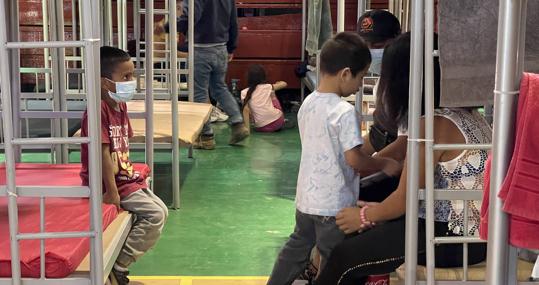 Adultos y niños matan el tiempo en el gimnasio mexicano que hace de refugio