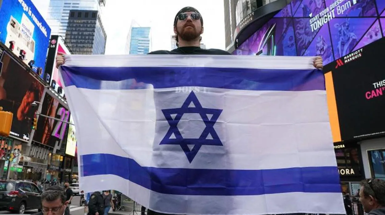 Un hombre sostiene una bandera de Israel en Times Square, en Nueva York
