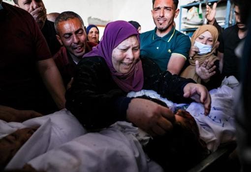 La abuela y los familiares de tres niños de la familia Al-Tanani, asesinados en un ataque israelí, lloran sobre sus cuerpos