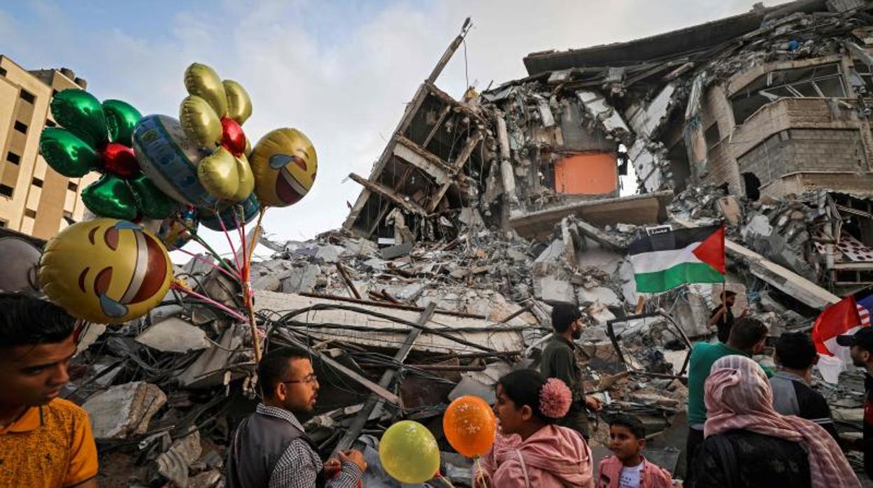 Un gazatí vende globos frente a un edificio destruido esta semana por la aviación israelí