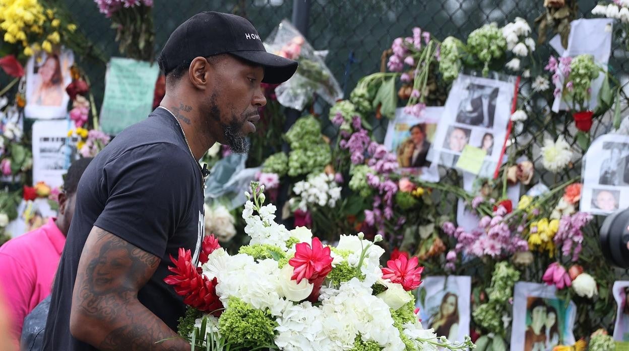 Un hombre lleva un ramo de flores al memorial de las víctimas del derrumbe del edificio, en Miami