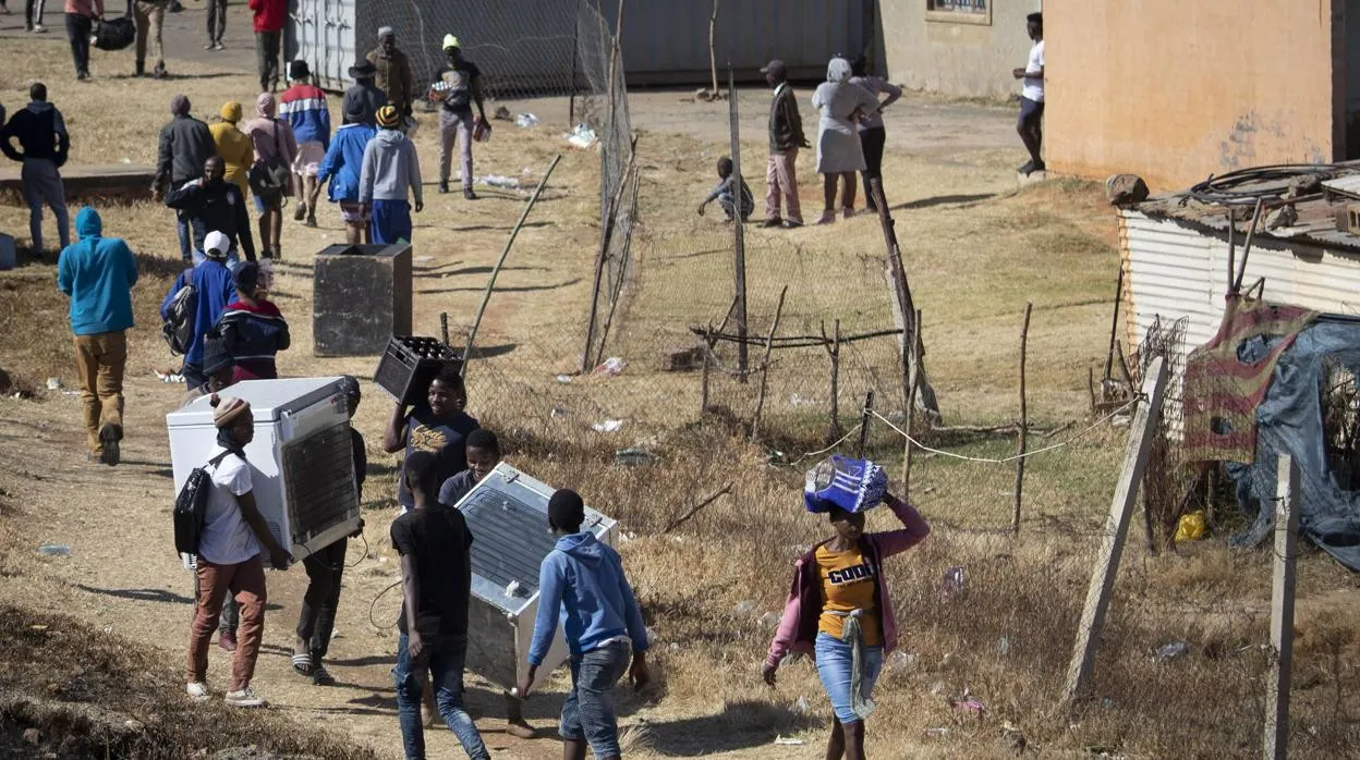 Los residentes llevan artículos saqueados de grandes almacenes y tiendas en el área de Soweto, cerca de Johannesburgo