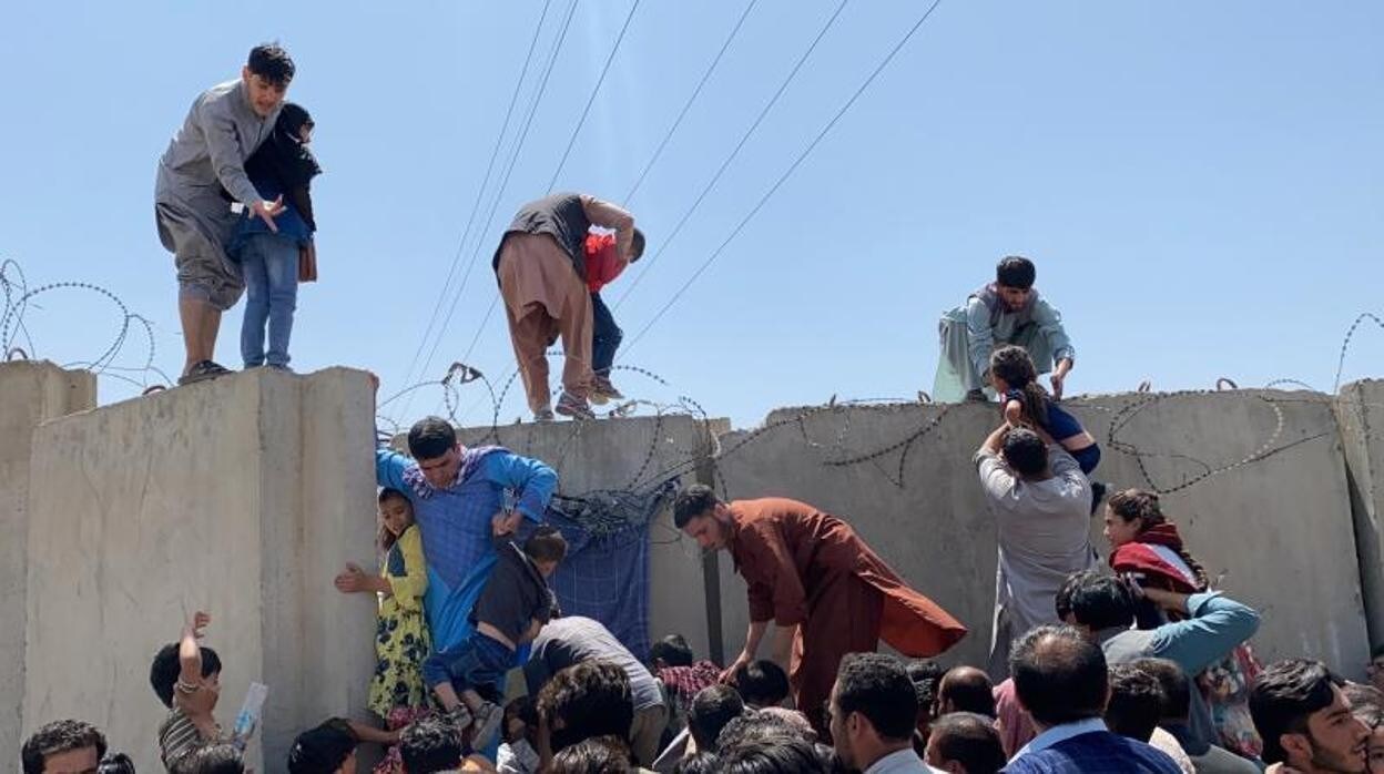 La gente lucha por cruzar el muro fronterizo del Aeropuerto Internacional Hamid Karzai para huir del país