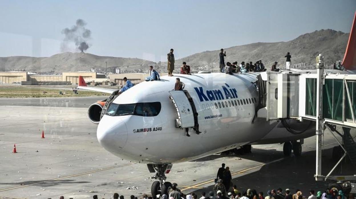 Afganos subidos al fuselaje de un avión en Kabul