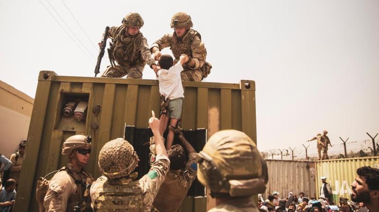 Fuerzas británicas, turcas y estadounidenses alzan a un niño en la evacuación del aeropuerto de Kabul