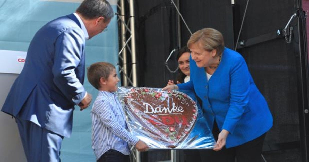 La canciller Angela Merkel recibe un tarta con la palabra 'gracias'