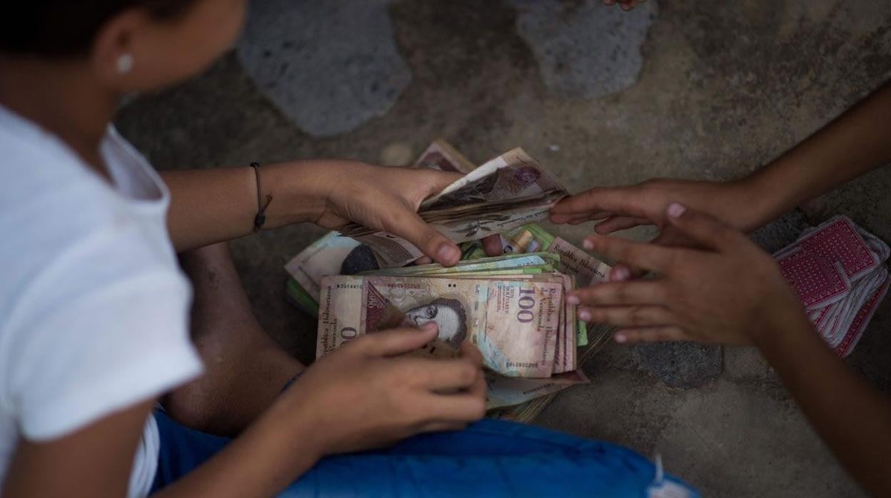 Unos niños juegan con billetes de bolívares