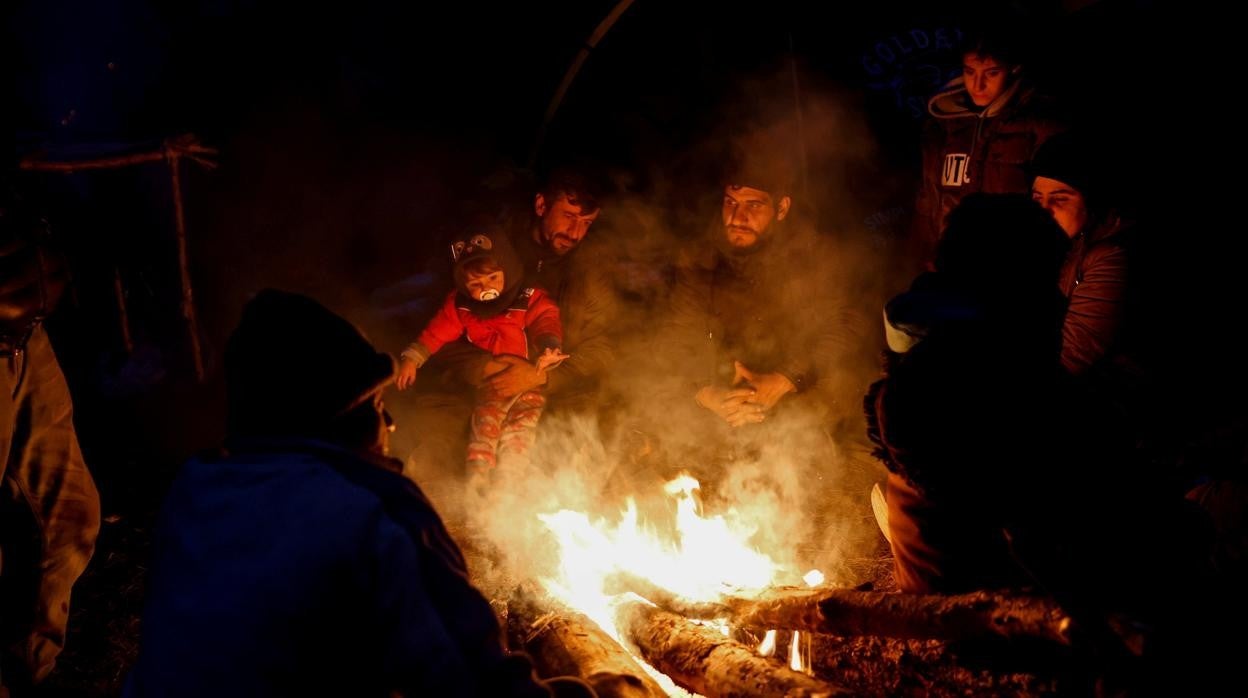 Un grupo de migrantes se reúne alrededor del fuego en un campamento improvisado en la frontera bielorruso-polaca en la región de Grodno, Bielorrusia