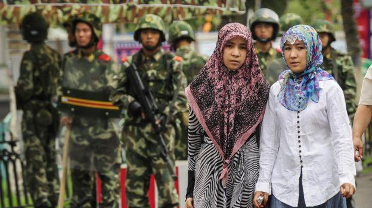 Mujeres de la etnia china uigur junto a policías