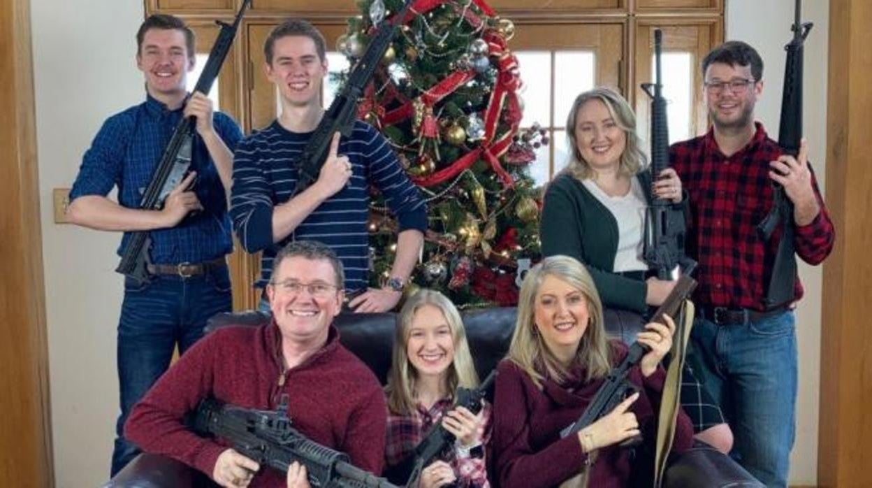 Massie y los miembros de su familia posan con rifles delante del árbol de Navidad