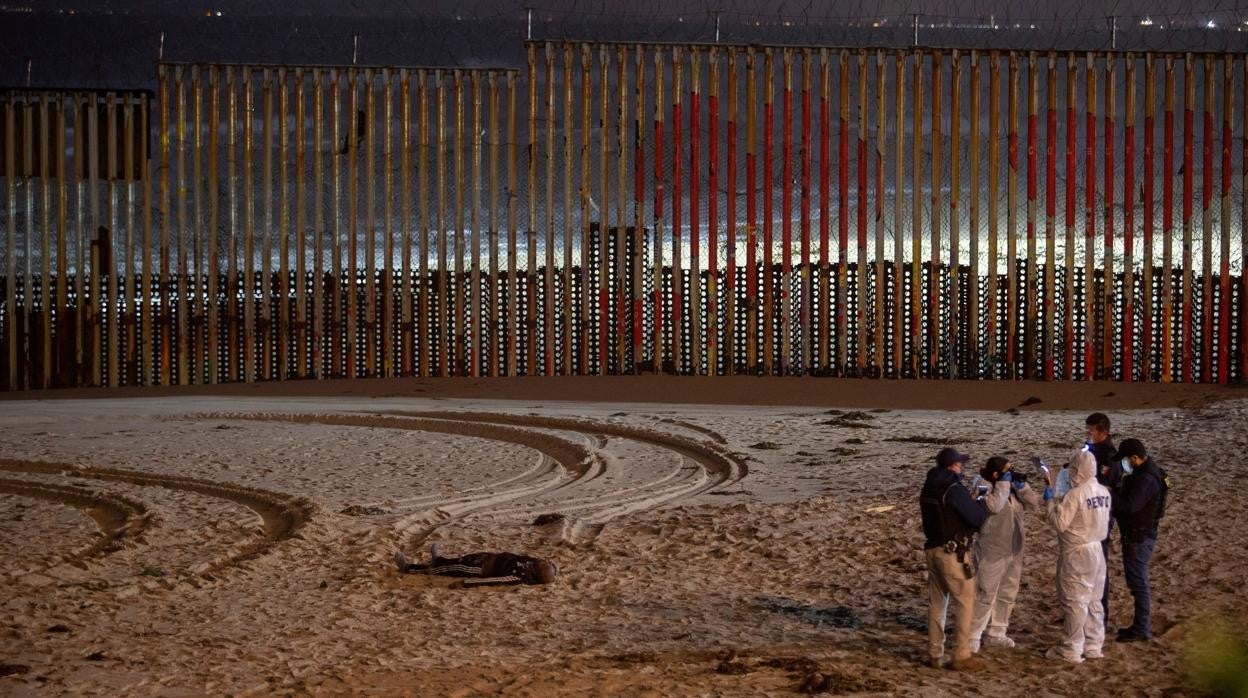 Agentes de la policía y un técnico forense conversan cerca de la valla fronteriza en Playas Tijuana