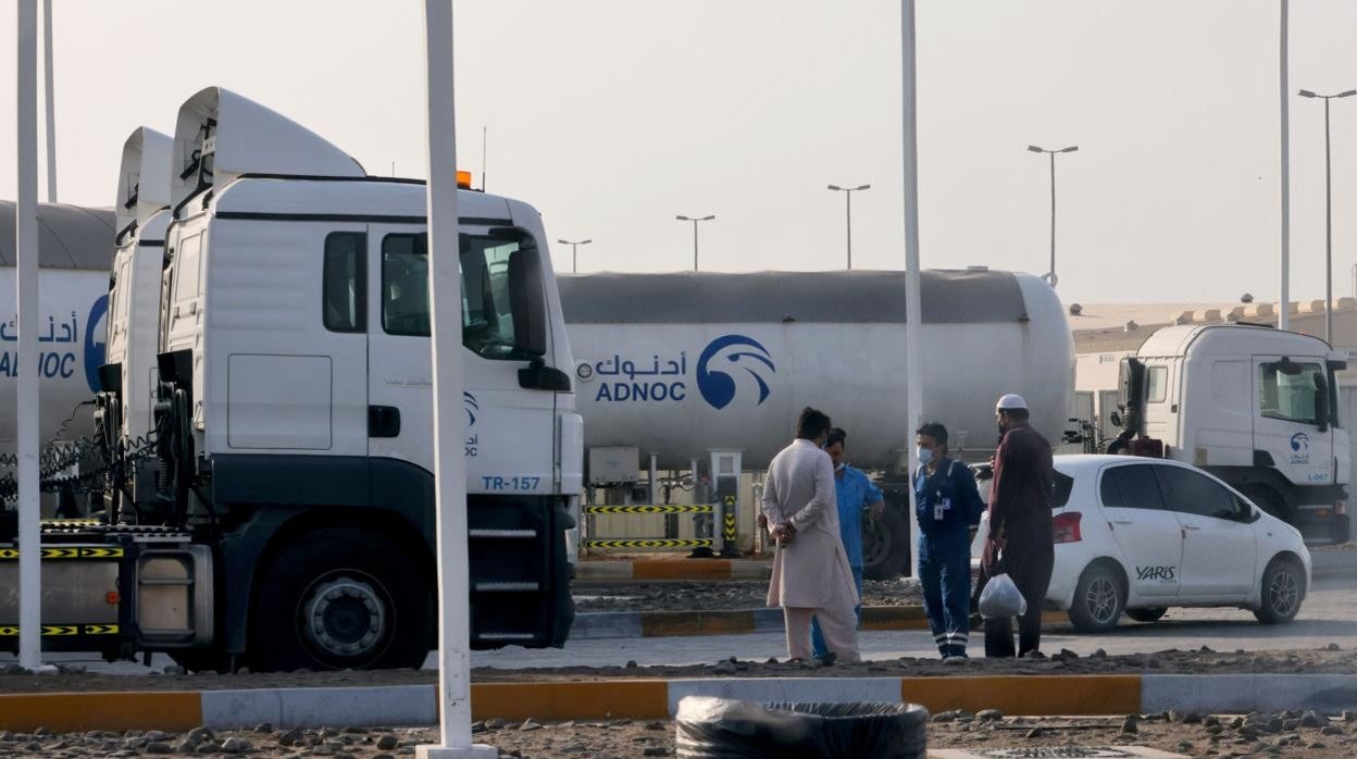 Cuatro hombres se paran frente a una instalación de almacenamiento del gigante petrolero ADNOC en la capital de los Emiratos Árabes Unidos, Abu Dhabi