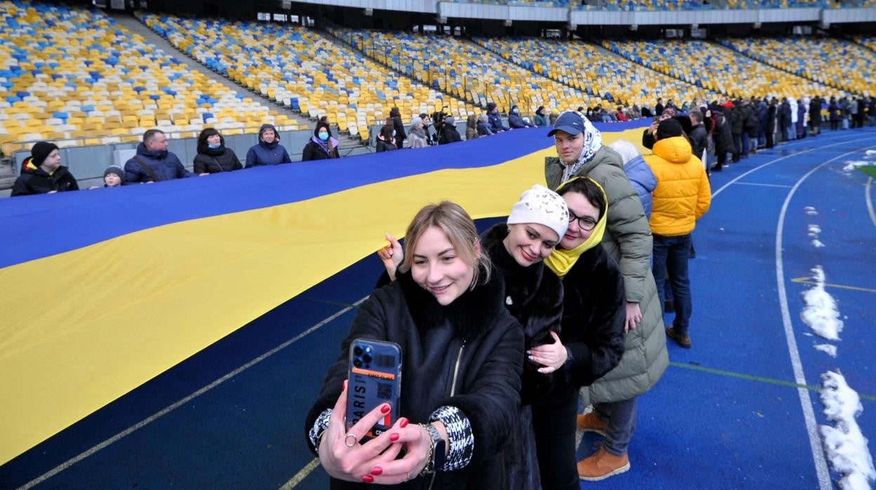 Un grupo de personas lleva una gran bandera de Ucrania para celebrar en Kiev el Día de la Unidad