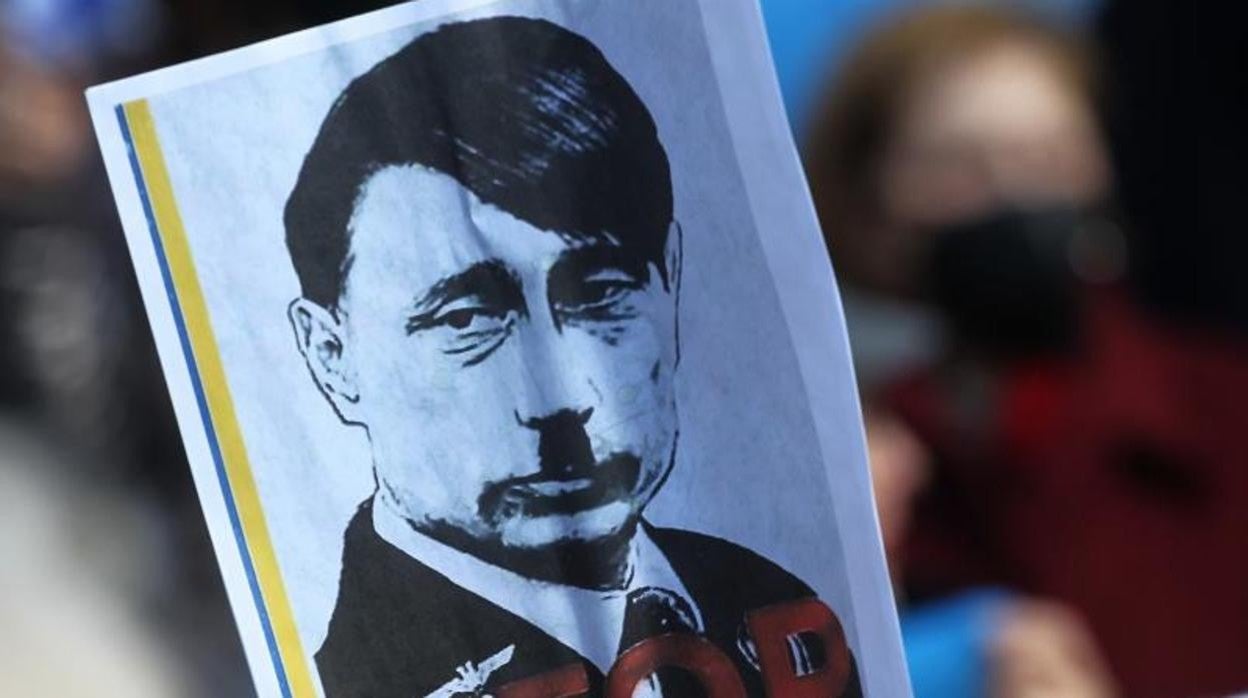 Manifestantes sostienen un montaje de un retrato de Putin modificado para que se parezca a Hitler