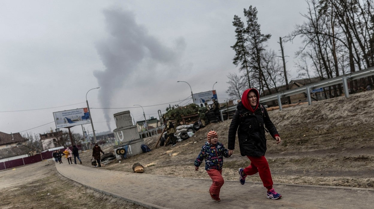 Una mujer huye a la carrera con un niño bajo los bombardeos rusos en la ciudad de Irpin