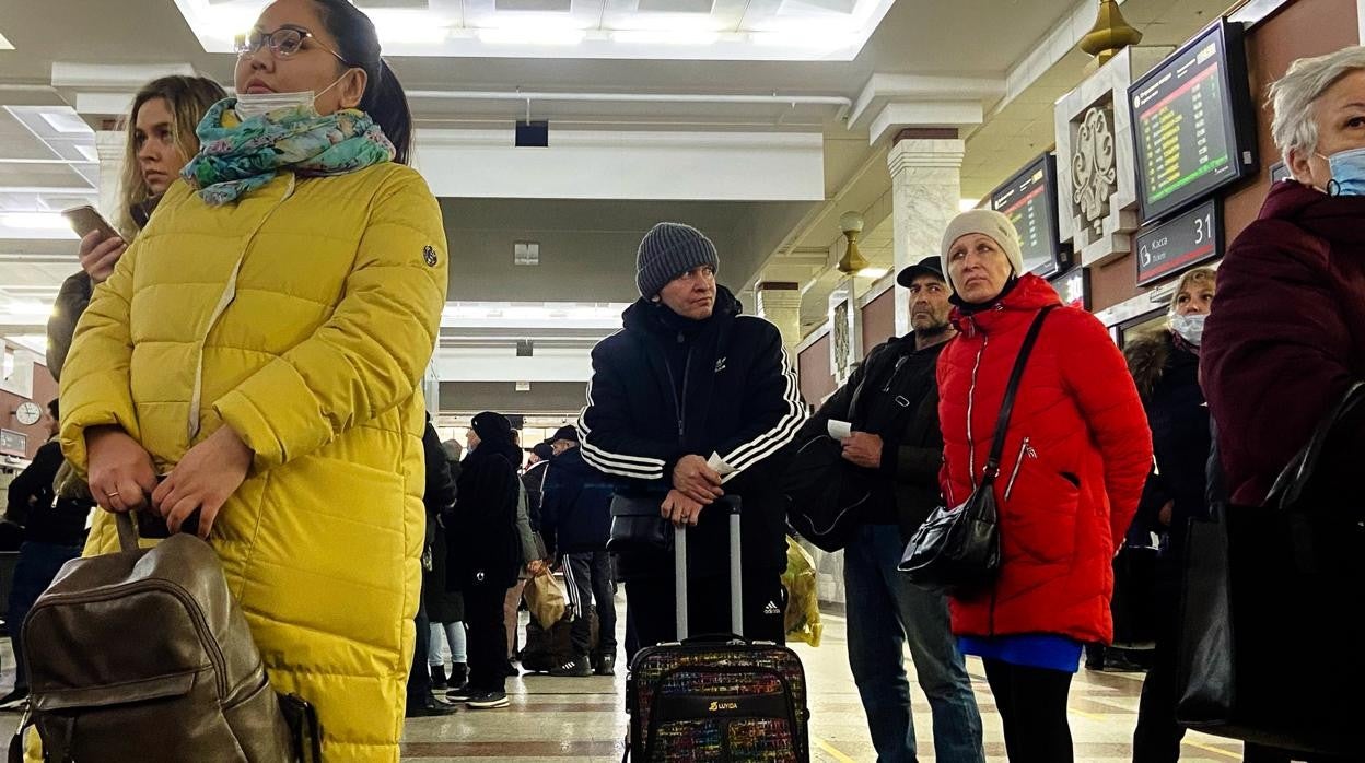 Dos personas esperan su turno en la estación de tren Kazanski (Moscú). Los Moscovitas deben esperar turnos de hasta 70 minutos para poder adquirir los billetes para los trenes con destino el sur del país. Tras el cierre del espacio aéreo, el tren es una de las pocas vías para viajar hasta la frontera.